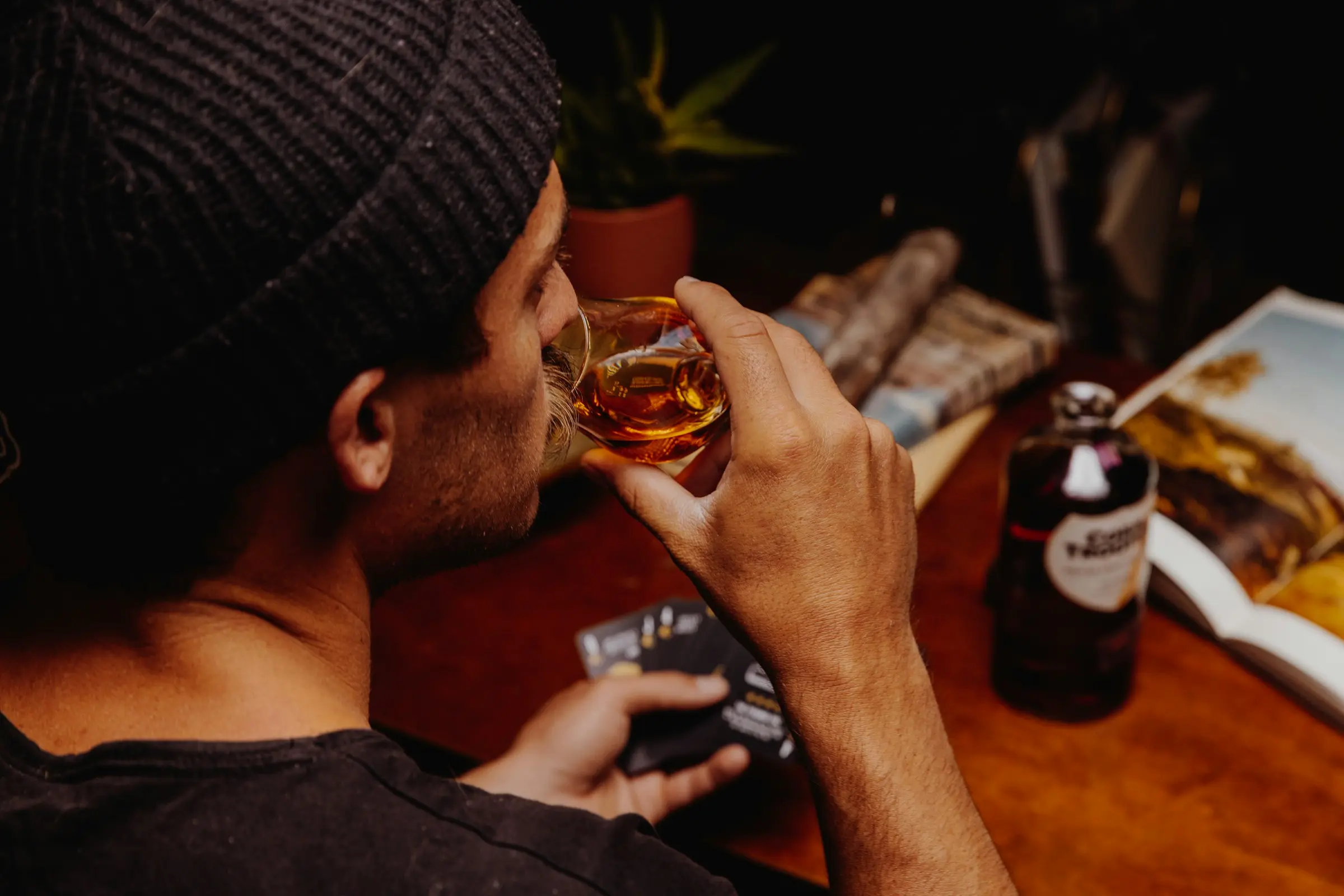 Uomo che assaggia un distillato ambrato seduto a un tavolo con dei sigari.